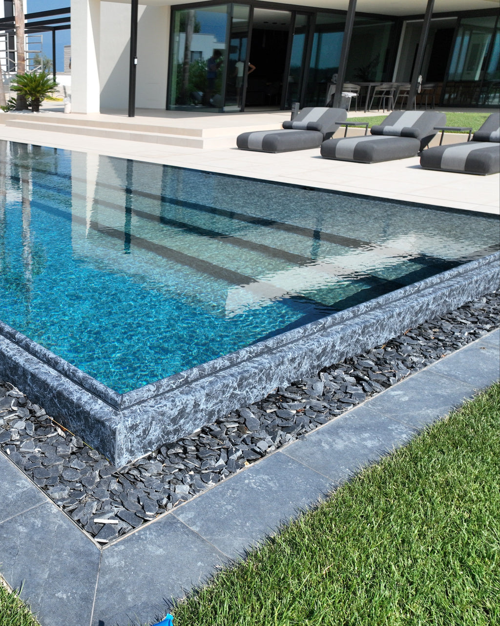 Piscina a sfioro con sbalzo, rivestimento nero marmorizzato