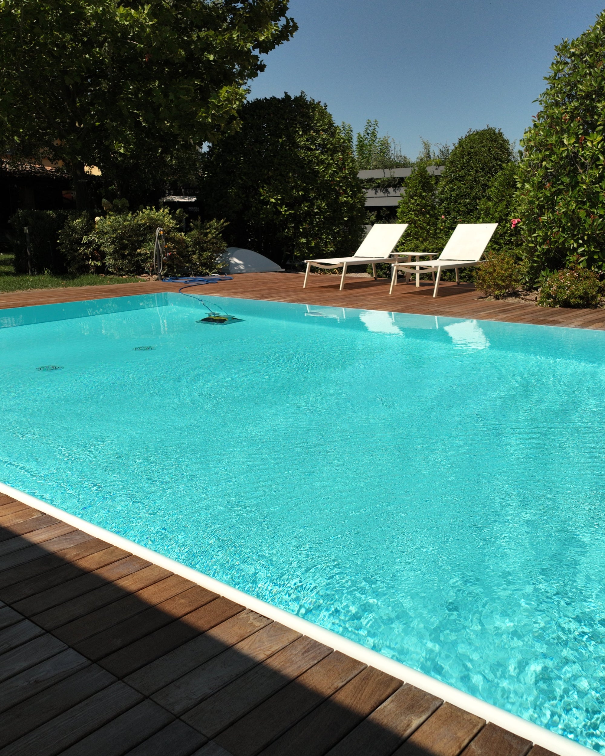 Piscina a sfioro rettangolare con pavimentazione color legno