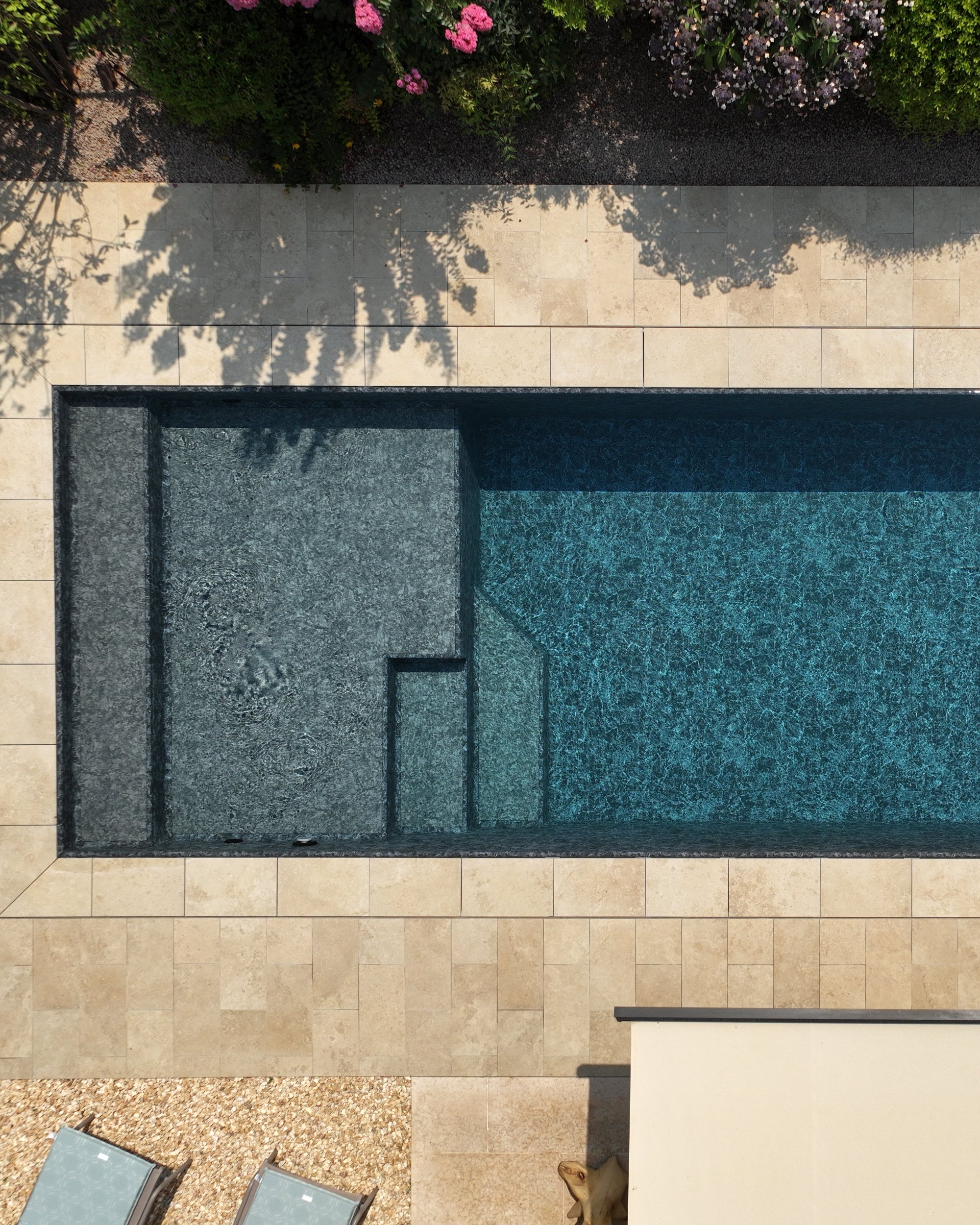 Piscina sfioro con spiaggia a tutta larghezza rivestimento nero marmorizzato